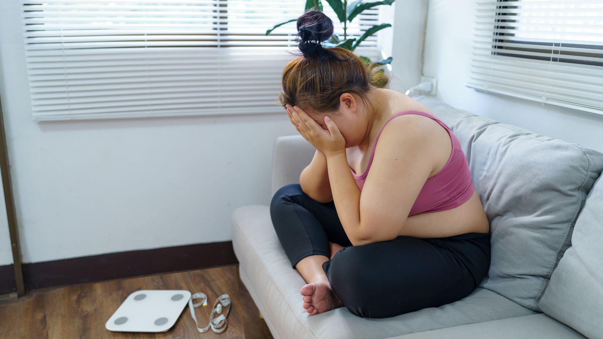 Frau sitzt verzweifelt auf dem Sofa, vor ihr liegt eine Waage