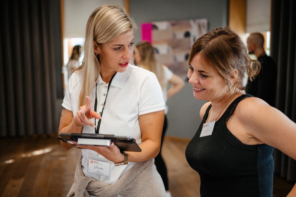 Vanessa zeigt einer Teilnehmerin mit Lipödem Beinen etwas auf dem iPad und erklärt den personalisierten Plan
