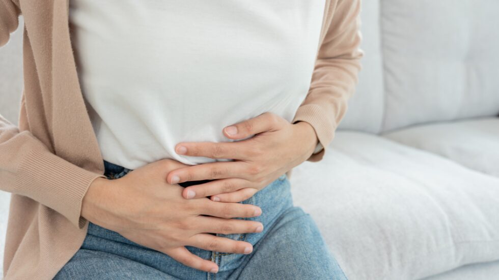 Frau hält sich an ihren Bauch als hätte sie Schmerzen.