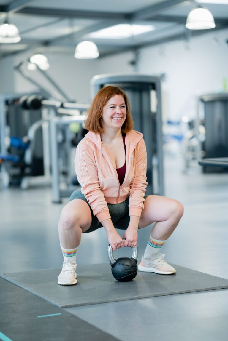 Teilnehmerin der Ernährungsberatung Körperverwandlung macht Frauen Krafttraining mit Kettlebell und zeigt eine korrekte Squat-Übung.