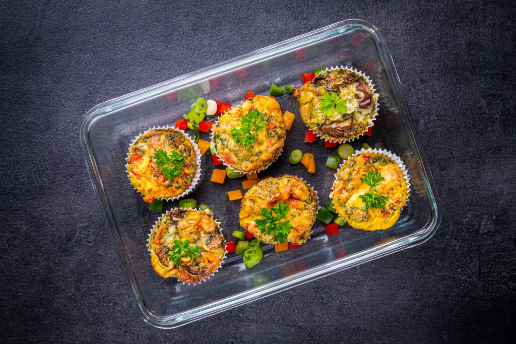 „Gemüsemuffins mit Käse und Kräutern in einer Meal Prep Box – bunte proteinreiche Mahlzeit für unterwegs oder als Frühstück“