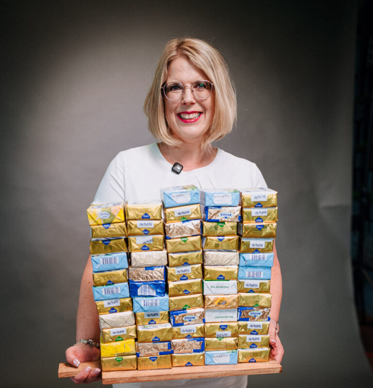 Bild einer Frau namens Stephanie, die 15 Kilo abgenommen hat. Sie trägt ihr abgenommenes Gewicht in Form von Butter. Inspirierende Geschichte über Abnehmen und mehr Lebensfreude